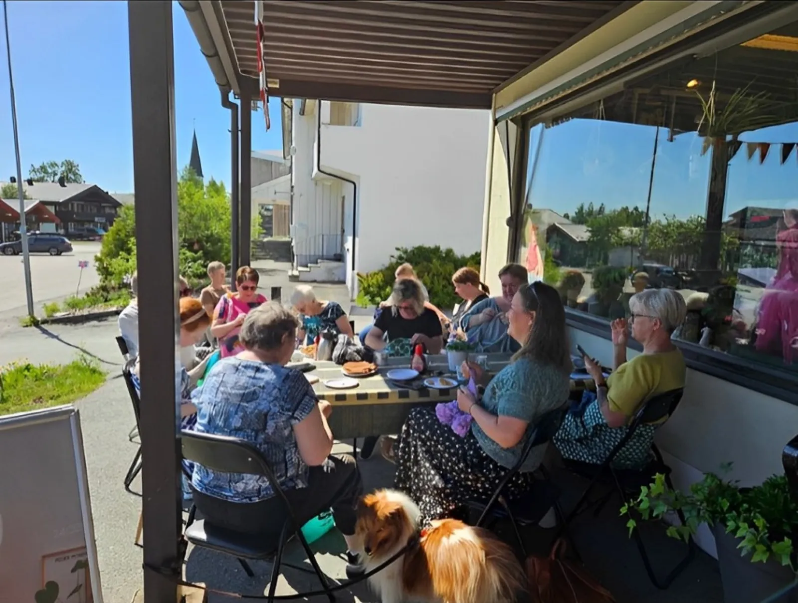 Strikkere samlet rundt et langbord på en solfylt veranda